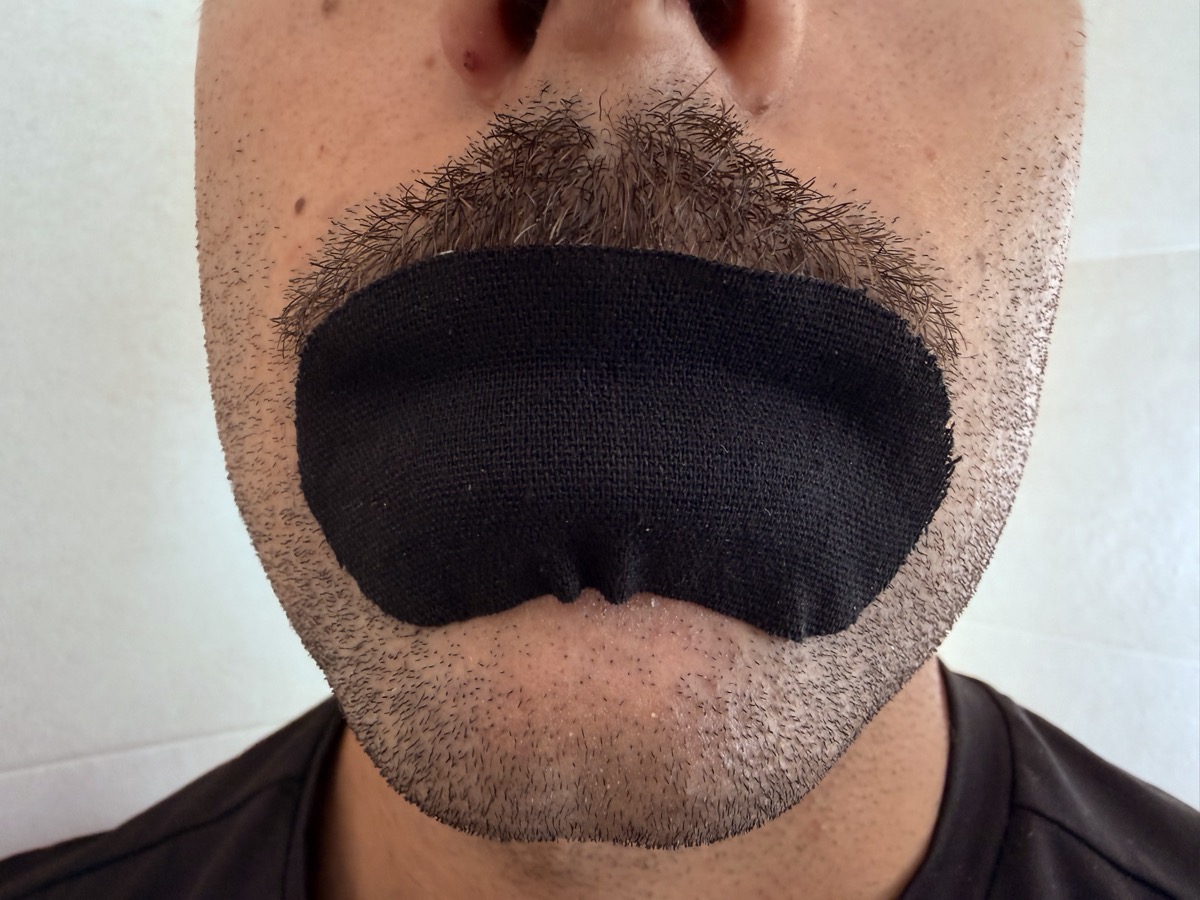 Primer plano de la tira bucal RAIAN colocada justo debajo del bigote y la barba, sobre la piel