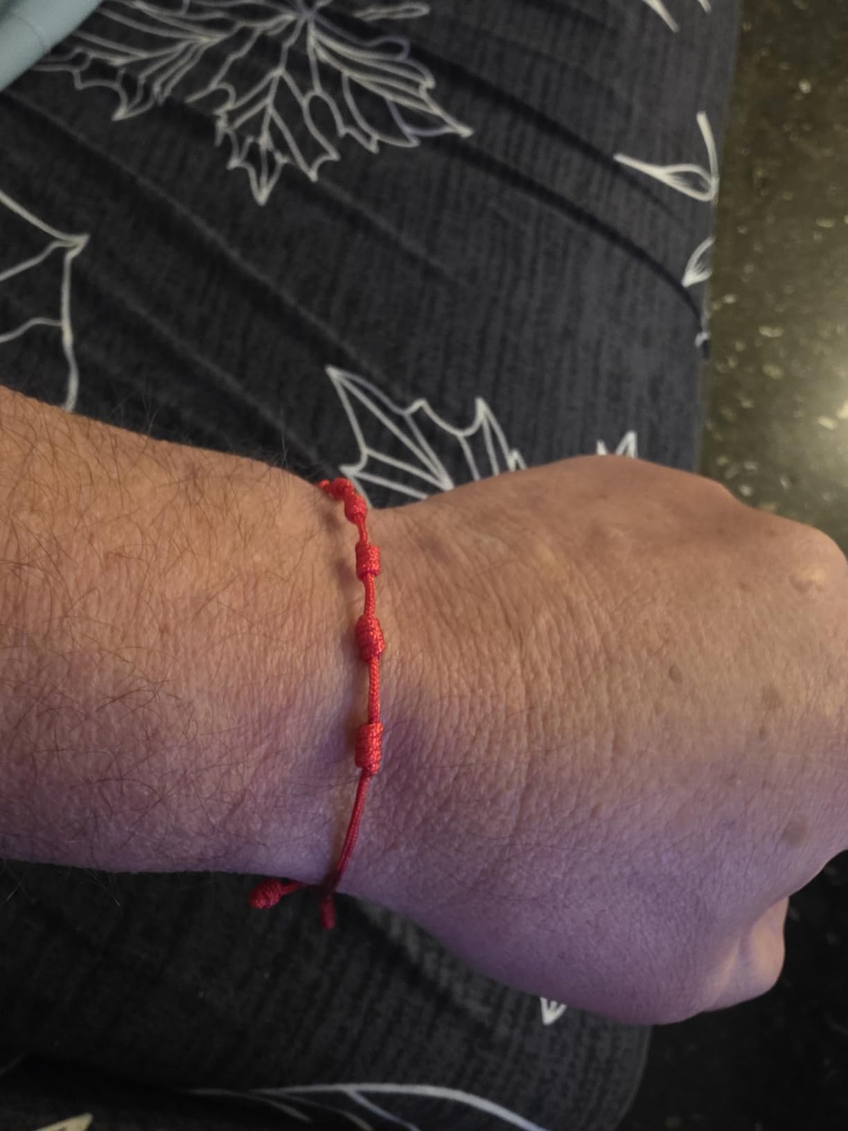 Detalle de pulsera roja de los 7 nudos en una muñeca